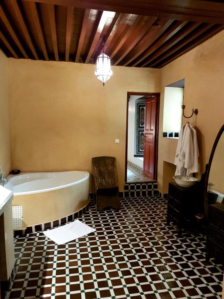 une salle de bain avec une baignoire, une table et une chaise dans l'établissement Riad Souafine, à Fès