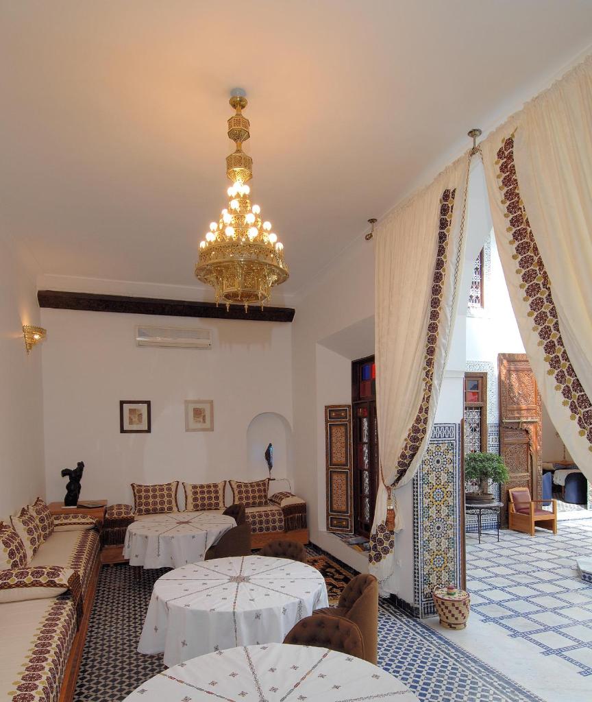 un salon avec deux tables et un lustre dans l'établissement Riad Souafine, à Fès