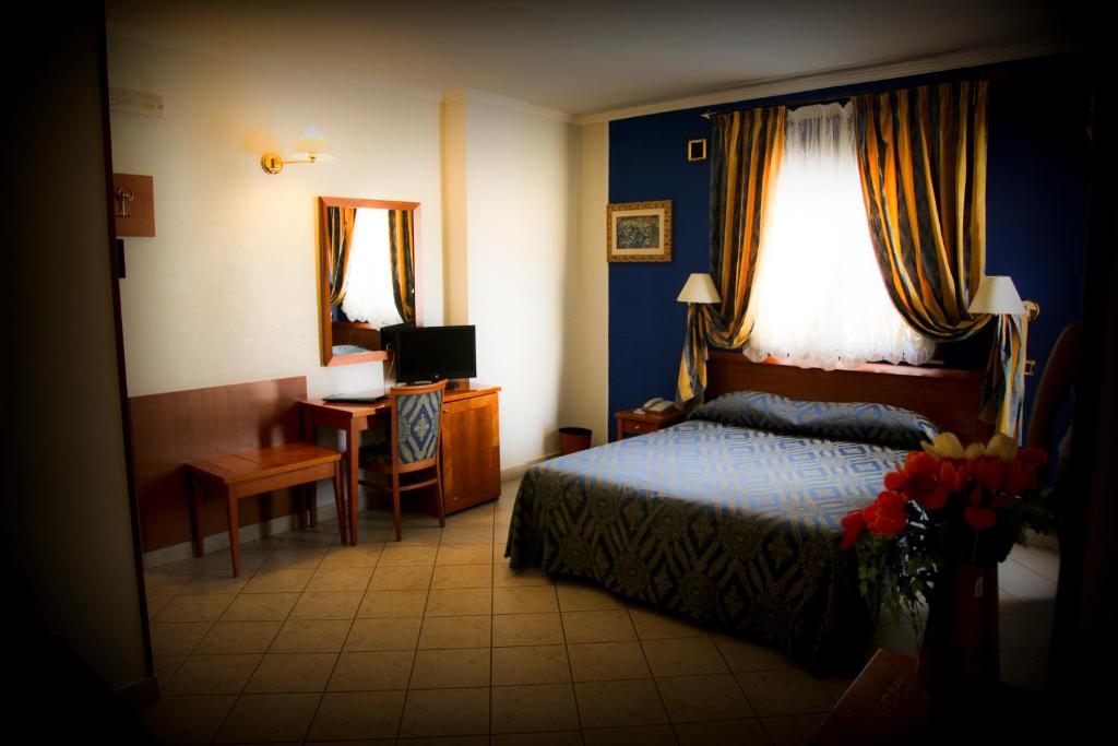 une chambre avec un lit et un bureau avec une télévision dans l'établissement Hotel Ristorante Rinelli, à Margherita di Savoia