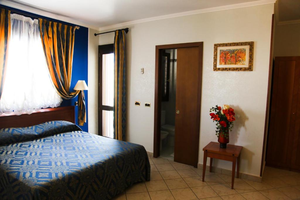 une chambre avec un lit et un vase de fleurs sur une table dans l'établissement Hotel Ristorante Rinelli, à Margherita di Savoia