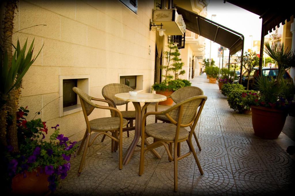 une table et des chaises assises à l'extérieur d'un bâtiment dans l'établissement Hotel Ristorante Rinelli, à Margherita di Savoia