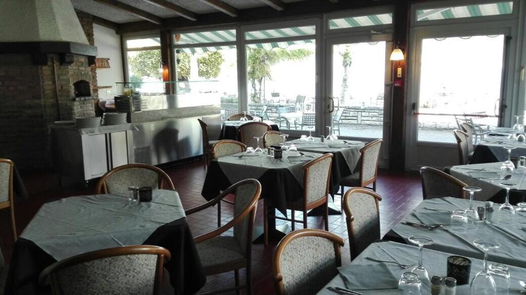 un restaurant avec des tables et des chaises dans une salle avec des fenêtres dans l'établissement Piccolo Hotel Direkt am See, à Brenzone 44 autres photos