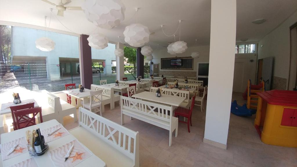 un restaurant avec des tables et des chaises blanches et des nuages dans l'établissement Hotel Milano 3S, à Bibione