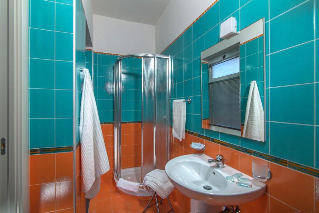 une salle de bain carrelée bleue avec un lavabo et une douche dans l'établissement Villa Comics, à Villammare