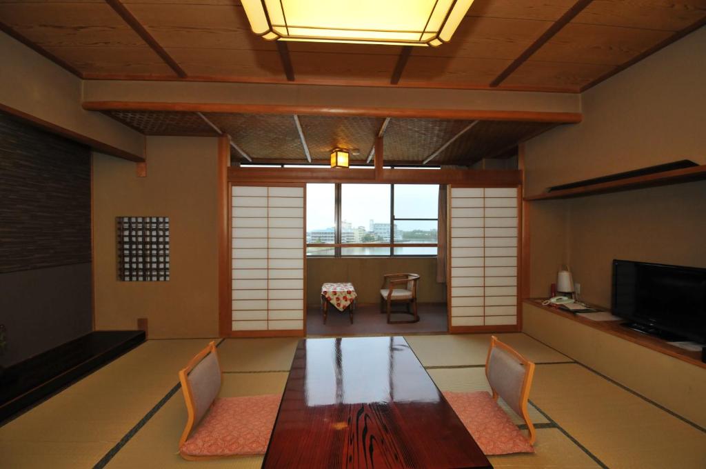 une pièce avec une table, des chaises et une télévision dans l'établissement Kohan-no-Yado Morimoto, à Kaga