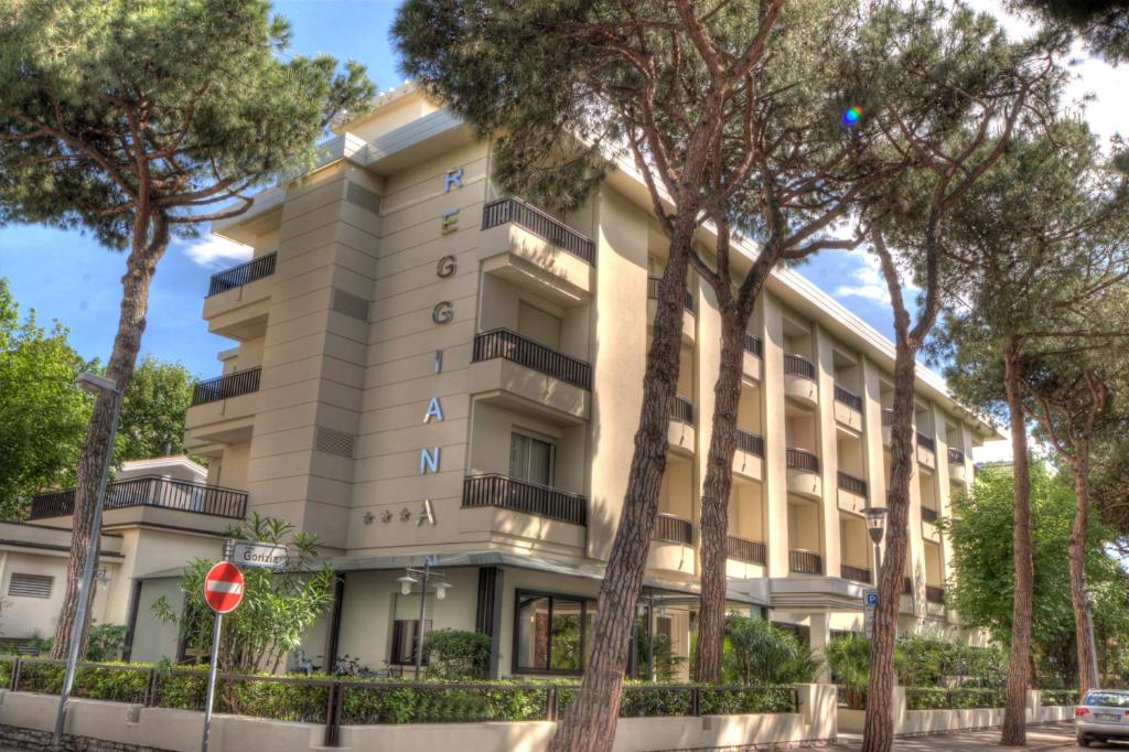 un immeuble d'appartements avec des arbres devant dans l'établissement Hotel Reggiana, à Riccione