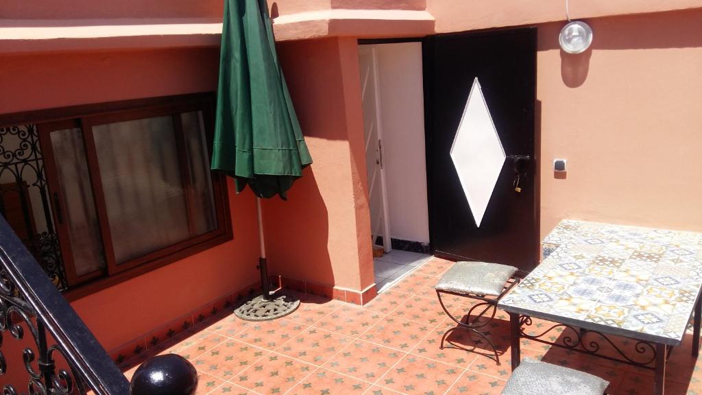 Cette chambre dispose d'une porte avec une table et un parasol vert. dans l'établissement Riad Lalla Zahra, à Marrakech