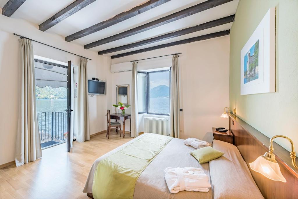 une chambre avec un grand lit et une grande fenêtre dans l'établissement Villa Belvedere Como Lake Relais, à Argegno