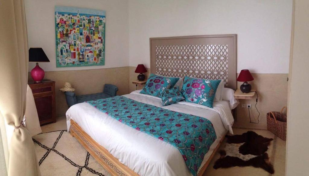 une chambre avec un grand lit avec des oreillers bleus dans l'établissement Jennat El Mossafir-Riad privé avec services, à Essaouira