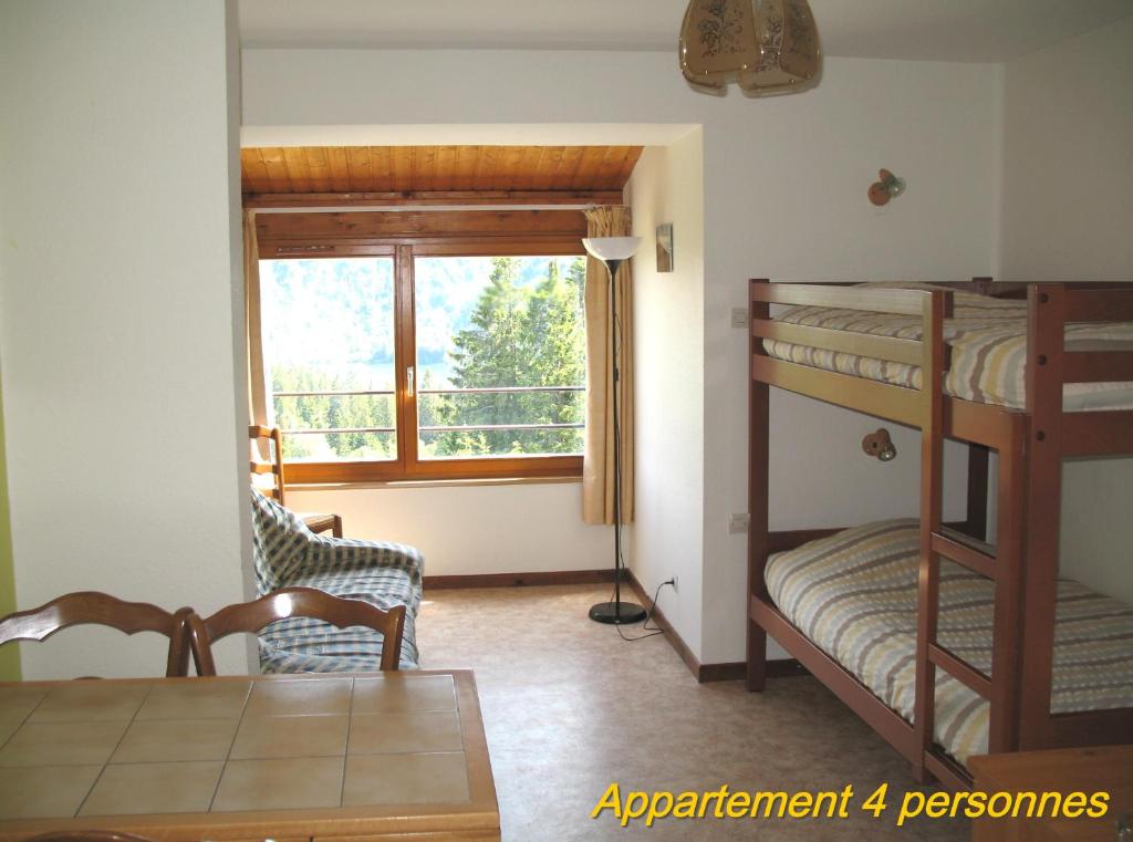 Cette chambre comprend 2 lits superposés, une table et une fenêtre. dans l'établissement Les Terrasses du Lac Blanc - Studios & Appartements, à Orbey