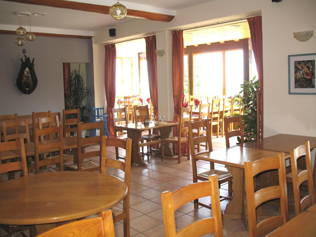 un restaurant avec des tables et des chaises en bois et des fenêtres dans l'établissement Les Terrasses du Lac Blanc - Studios & Appartements, à Orbey