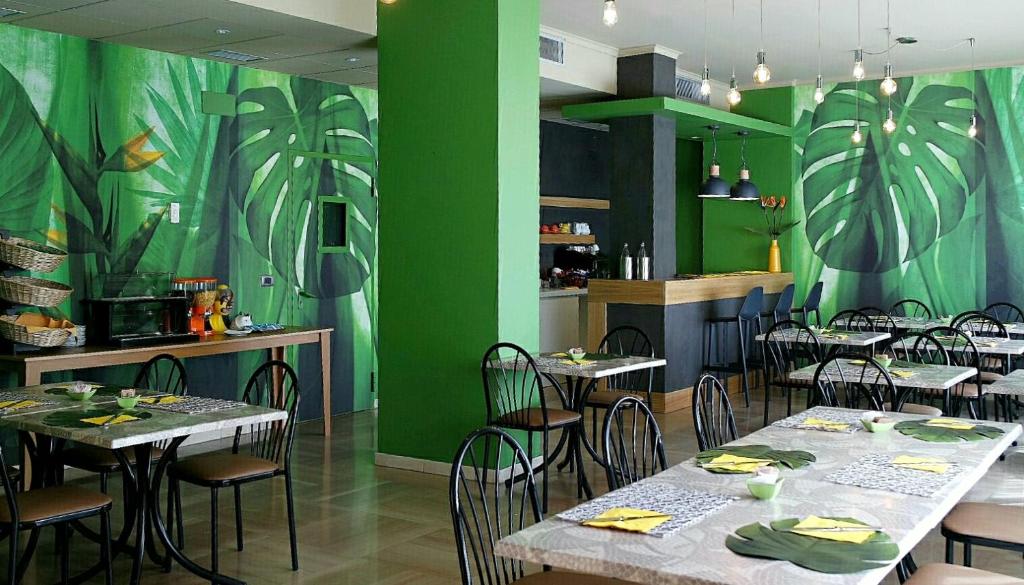un restaurant avec des tables, des chaises et des murs verts dans l'établissement Sait Hotel & BB, à Terme Vigliatore