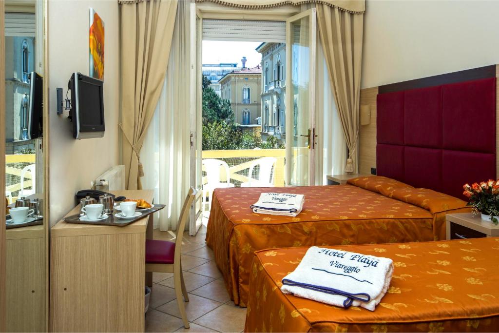 une chambre d'hôtel avec deux lits et un balcon dans l'établissement Hotel Playa, à Viareggio