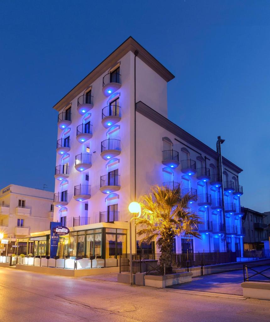 un grand bâtiment blanc avec des lumières bleues dessus dans l'établissement Hotel Emilia, à Rimini