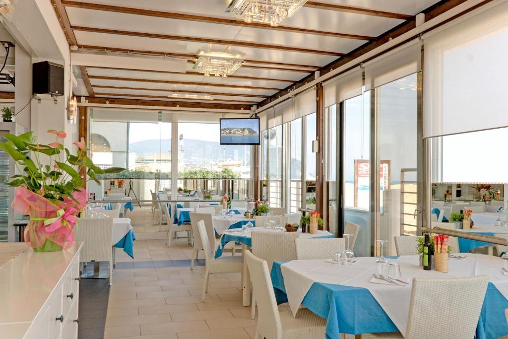 un restaurant avec des tables et des chaises blanches et des fenêtres dans l'établissement Il Conero Mare, à Numana