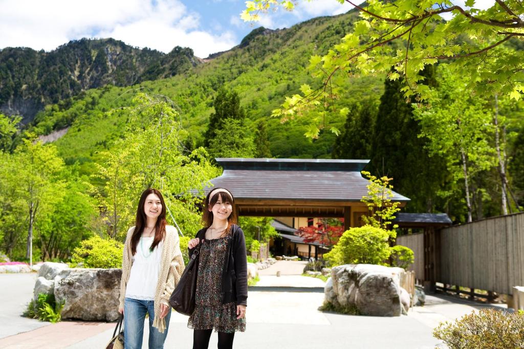 deux filles debout devant un bâtiment dans l'établissement Miyama Ouan Kyoritsu Resort, à Takayama