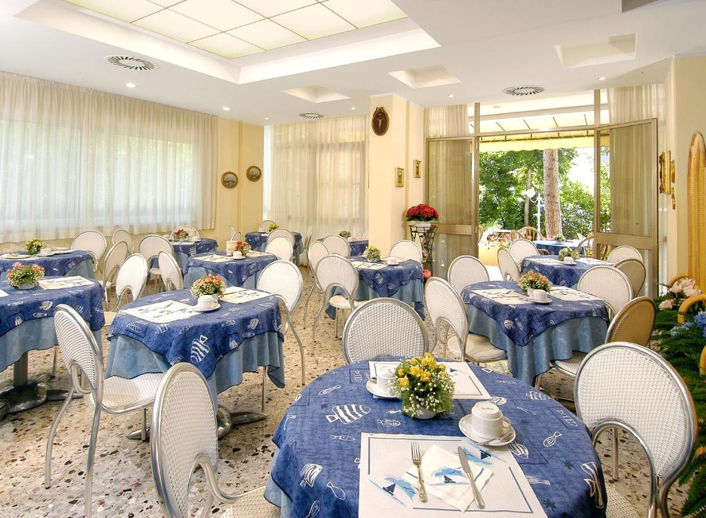 une salle de banquet avec des tables bleues et des chaises blanches dans l'établissement Hotel Cristina Hospitality Centrale, à Riccione
