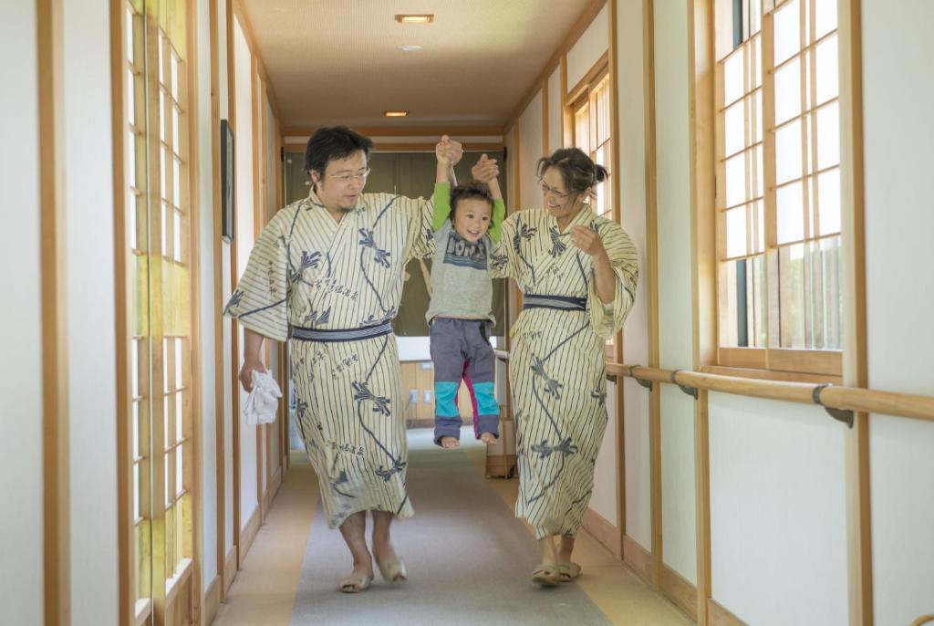 3 personnes en kimonos marchant dans un couloir avec un enfant dans l'établissement Nakamurakan, à Takayama