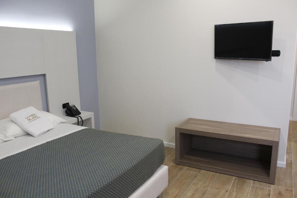 une chambre avec un lit et une télévision au mur dans l'établissement La Porta del Sole Hotel & Village, à San Ferdinando