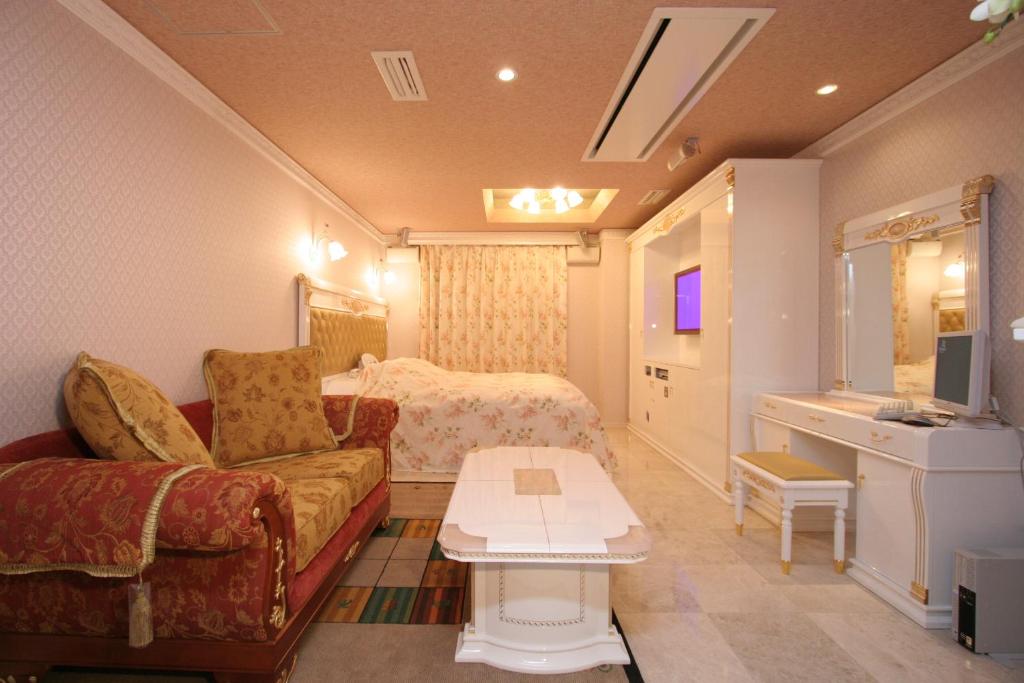 un salon avec un canapé et un lit dans l'établissement Hotel AtoZ Saku (Adult Only), à Saku