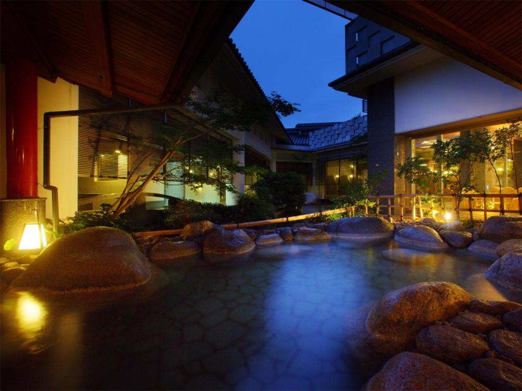 un bâtiment avec piscine d'eau en face d'un bâtiment dans l'établissement Hotel New Mitoya, à Sendai