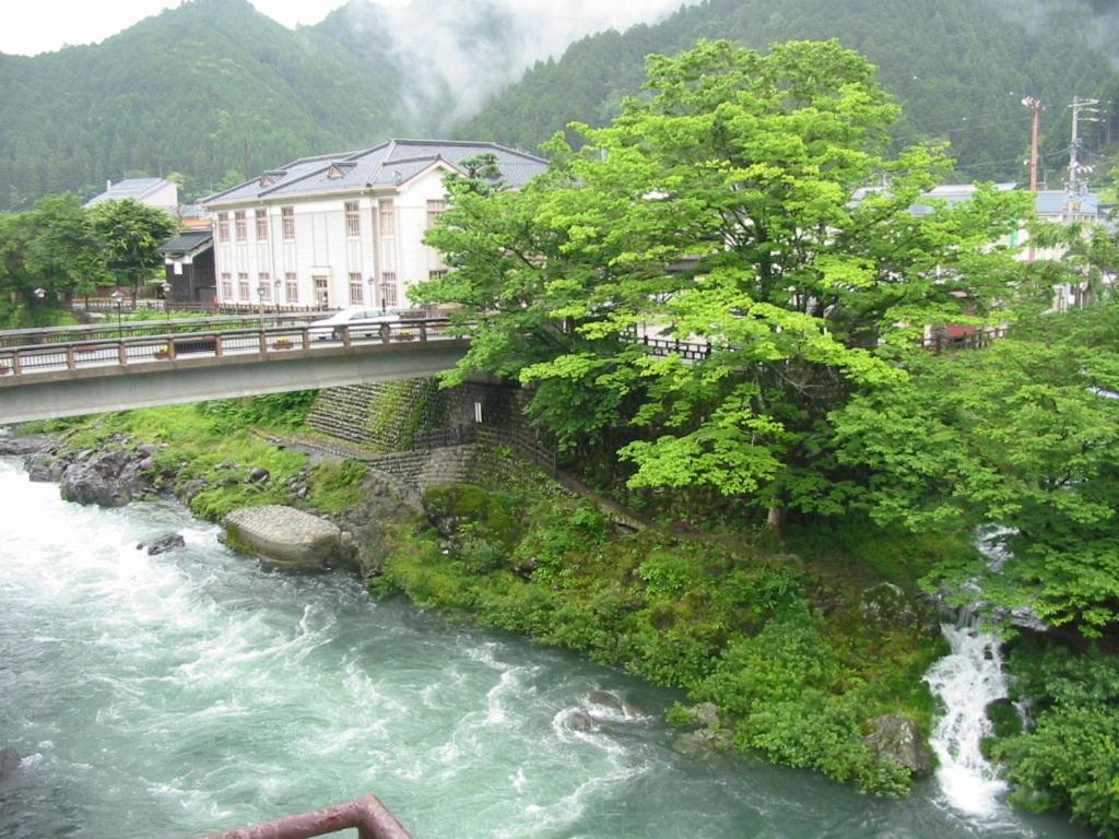 un pont sur une rivière avec une cascade dans l'établissement Miharaya Ryokan, à Gujō