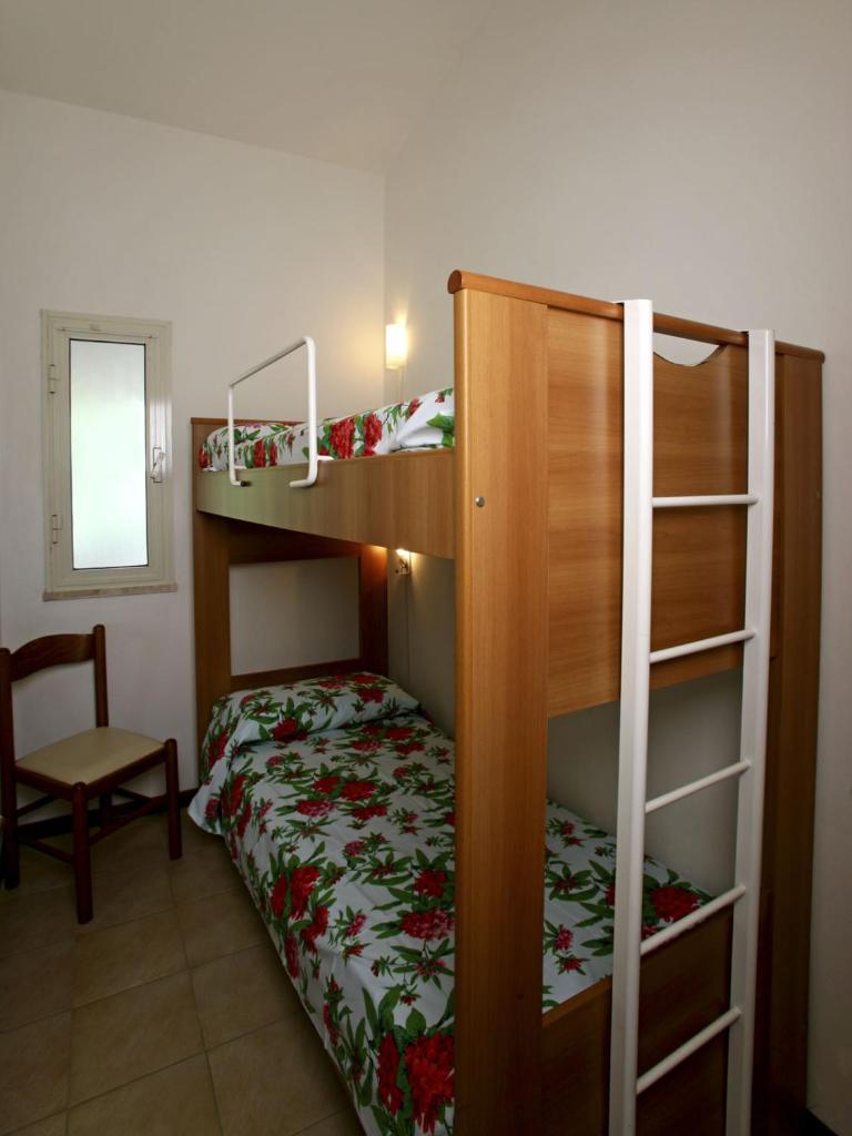 - une chambre avec 2 lits superposés et une chaise dans l'établissement Giannella Appartamenti, à Orbetello