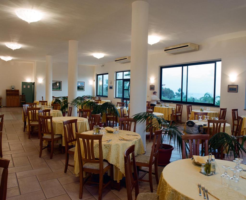 un restaurant avec des tables et des chaises dans une salle dans l'établissement Villaggio Pineta Petto Bianco, à Capo Vaticano
