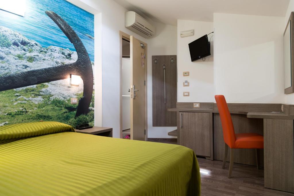 une chambre d'hôtel avec un lit, un bureau et une télévision dans l'établissement Hotel Miramare, à Pineto