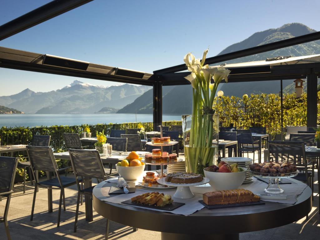 une table avec de la nourriture dessus avec vue sur l'eau dans l'établissement Filario Hotel & Residences, à Lezzeno