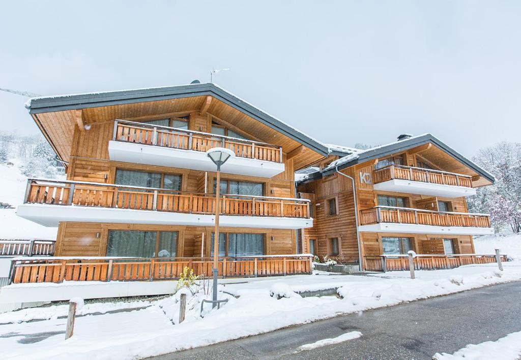 un grand bâtiment en bois avec de la neige devant lui dans l'établissement K2 by Alpine Resorts, aux Gets