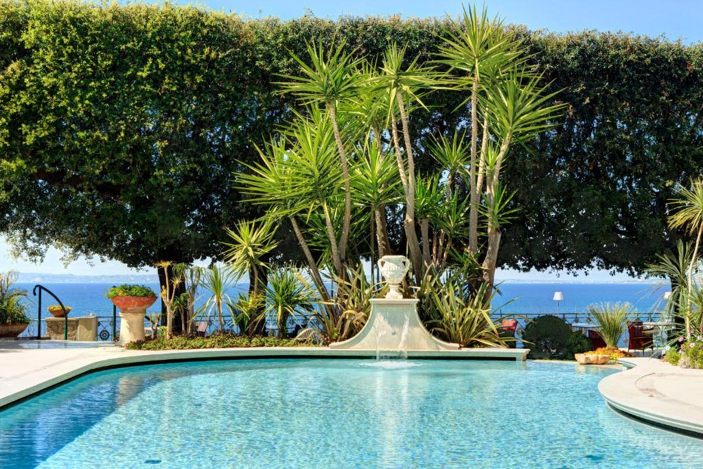 une piscine avec une fontaine devant des arbres dans l'établissement Grand Hotel Ambasciatori, à Sorrente