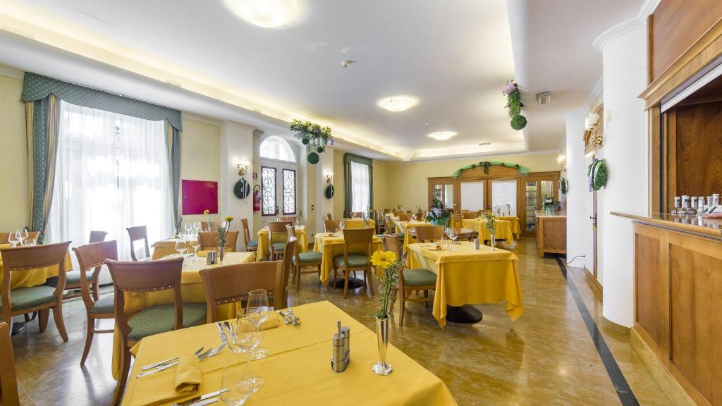 un restaurant avec des tables et des chaises et un tissu de table jaune dans l'établissement Hotel Ville Bianchi, à Grado