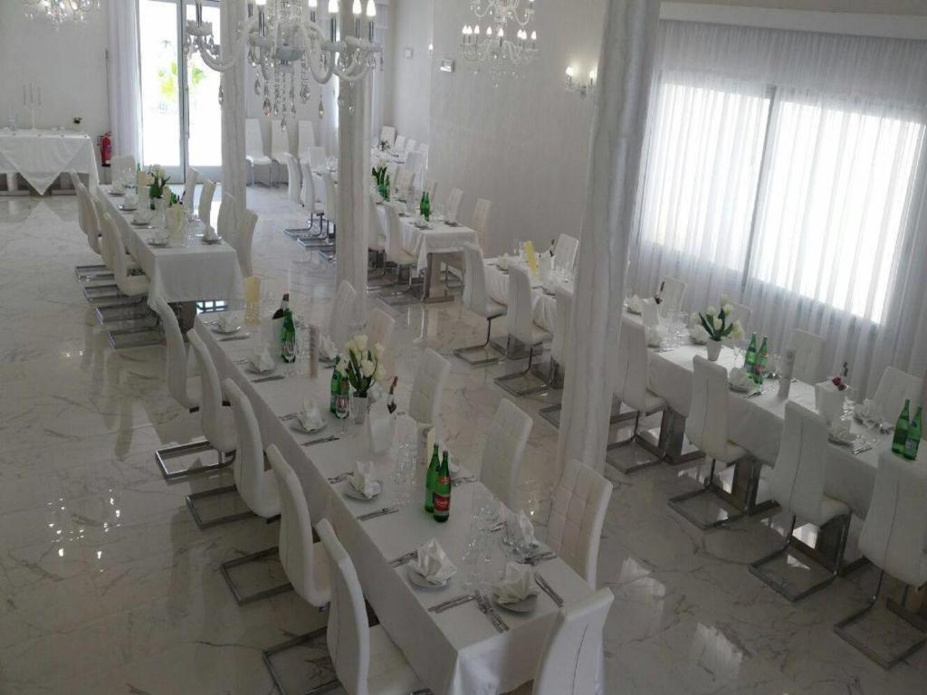 une salle de banquet avec des tables blanches et des chaises blanches dans l'établissement Hotel Paladini, à Porto Cesareo