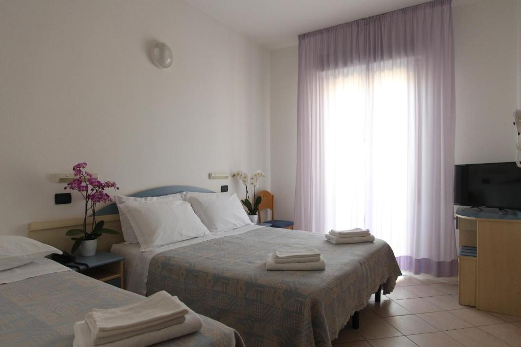 une chambre d'hôtel avec deux lits et une télévision dans l'établissement Hotel Giorg - WaterPark Free Entrance, à Rimini 60 autres photos