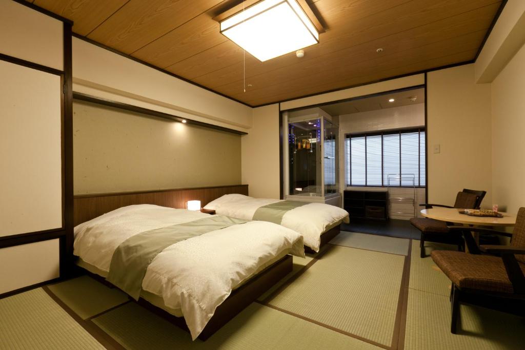 une chambre avec deux lits et une table et une fenêtre dans l'établissement Tosagyoen, à Kōchi