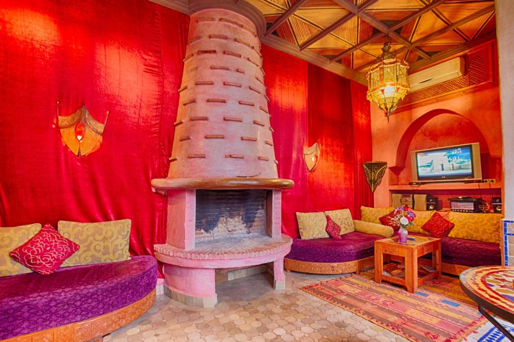 d'un salon avec une cheminée et des murs rouges. dans l'établissement Riad Kenzo, à Marrakech