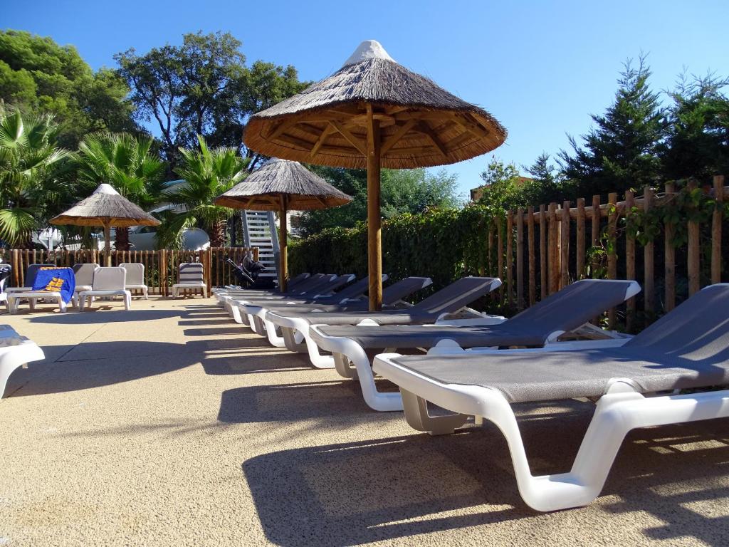 - une rangée de chaises longues avec parasols et chaises dans l'établissement Camping de la Treille, à Cavalaire-sur-Mer