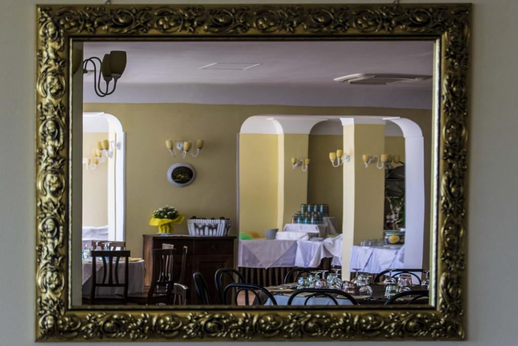 un miroir reflétant une salle à manger avec une table et des chaises dans l'établissement Hotel Baia, à Palinuro 45 autres photos