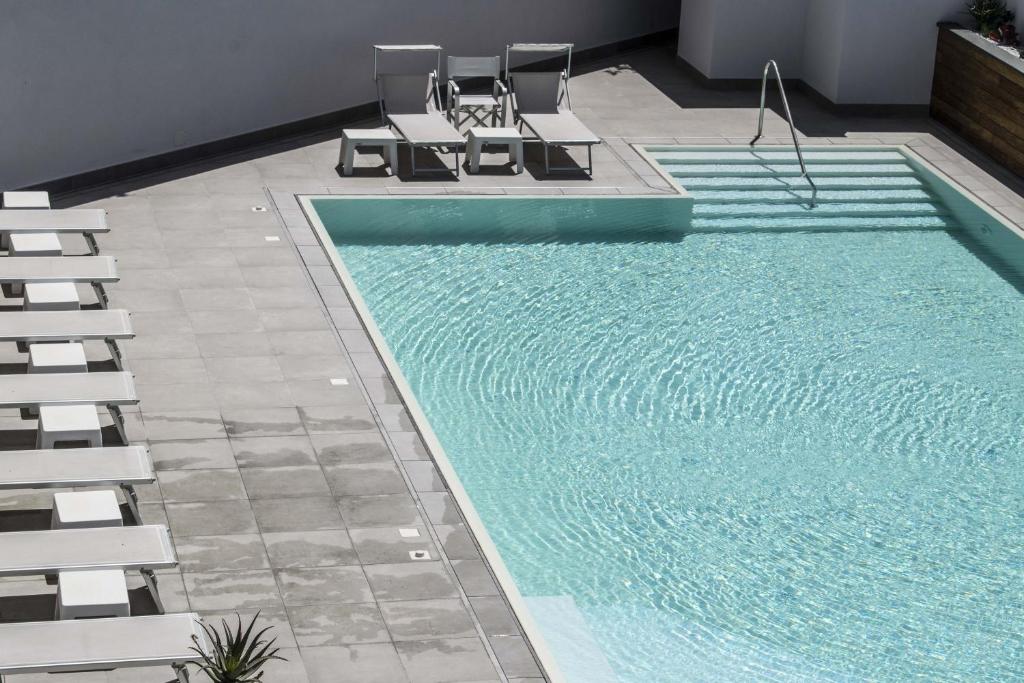 une piscine avec deux chaises longues et une piscine dans l'établissement Hotel Baia, à Palinuro
