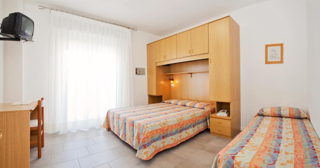 une chambre d'hôtel avec deux lits et une armoire dans l'établissement Hotel Augusta, à Caorle