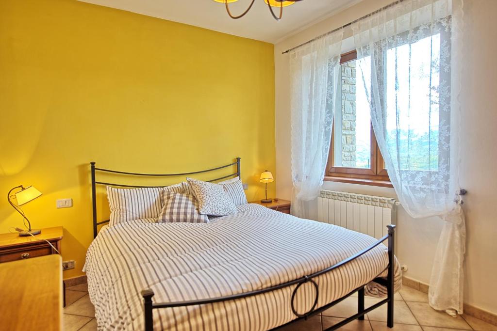 une chambre avec un lit aux murs jaunes et une fenêtre dans l'établissement Casale Daniele by PosarelliVillas, à Pratovecchio 36 autres photos