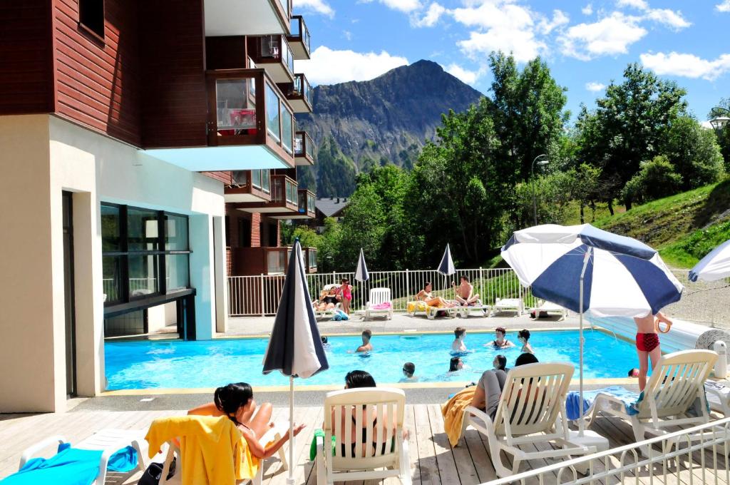 - un groupe de personnes assis sur des chaises au bord de la piscine dans l'établissement Résidence Goélia Les Terrasses du Corbier, au Corbier