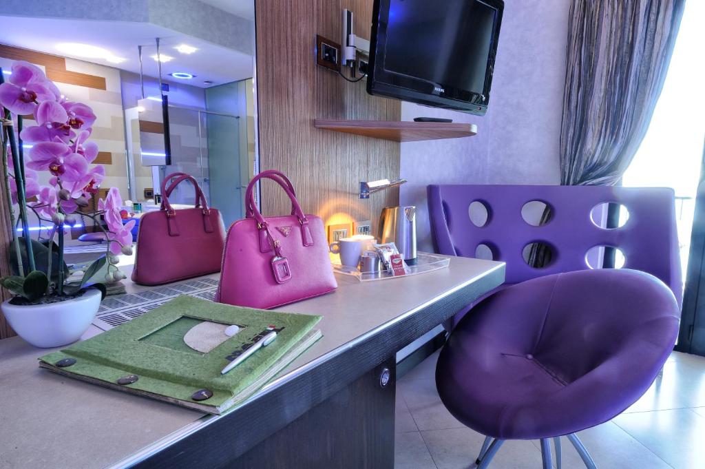 La salle de bains est pourvue de chaises violettes et d'une coiffeuse avec un porte-monnaie rose. dans l'établissement Mare Hotel, à Savone