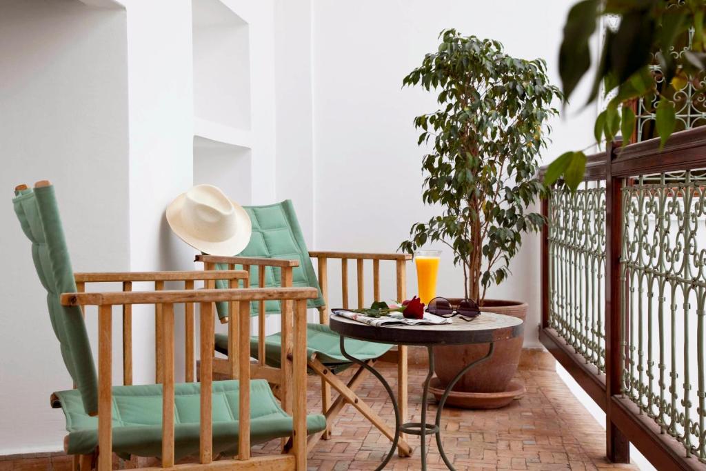 - un balcon avec deux chaises et une table avec une boisson dans l'établissement Riad Les Bougainvilliers, à Marrakech