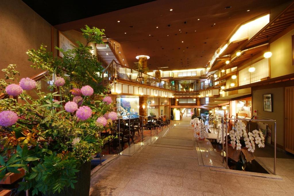 un couloir avec des tables et des fleurs dans un bâtiment dans l'établissement Shoenso Hozugawatei, à Kameoka