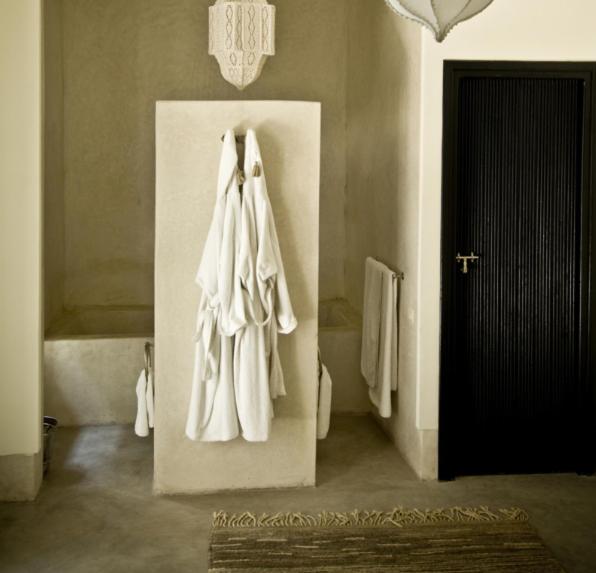 La salle de bains est pourvue de serviettes blanches accrochées au mur. dans l'établissement Riad First, à Marrakech