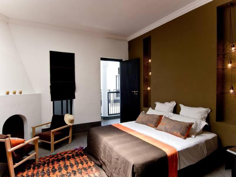 - une chambre avec un grand lit et une cheminée dans l'établissement Riad First, à Marrakech