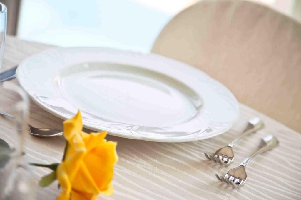 une plaque, deux fourchettes et une fleur jaune sur une table dans l'établissement Hotel Silver, à Cesenatico