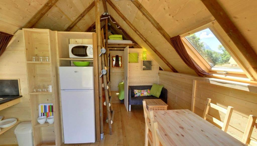 - une cuisine avec un réfrigérateur et une table dans une petite maison dans l'établissement Camping le Petit Liou Sites & Paysages, à Baratier